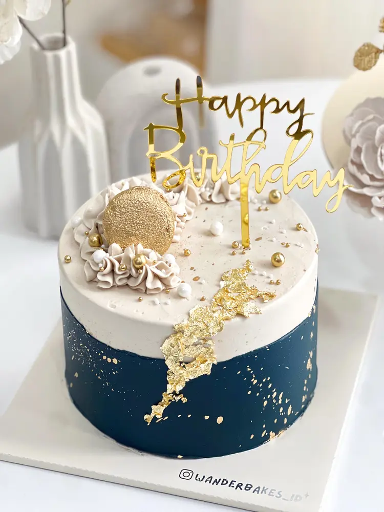 Cake biru navy dengan aksen emas dan topper Happy Birthday