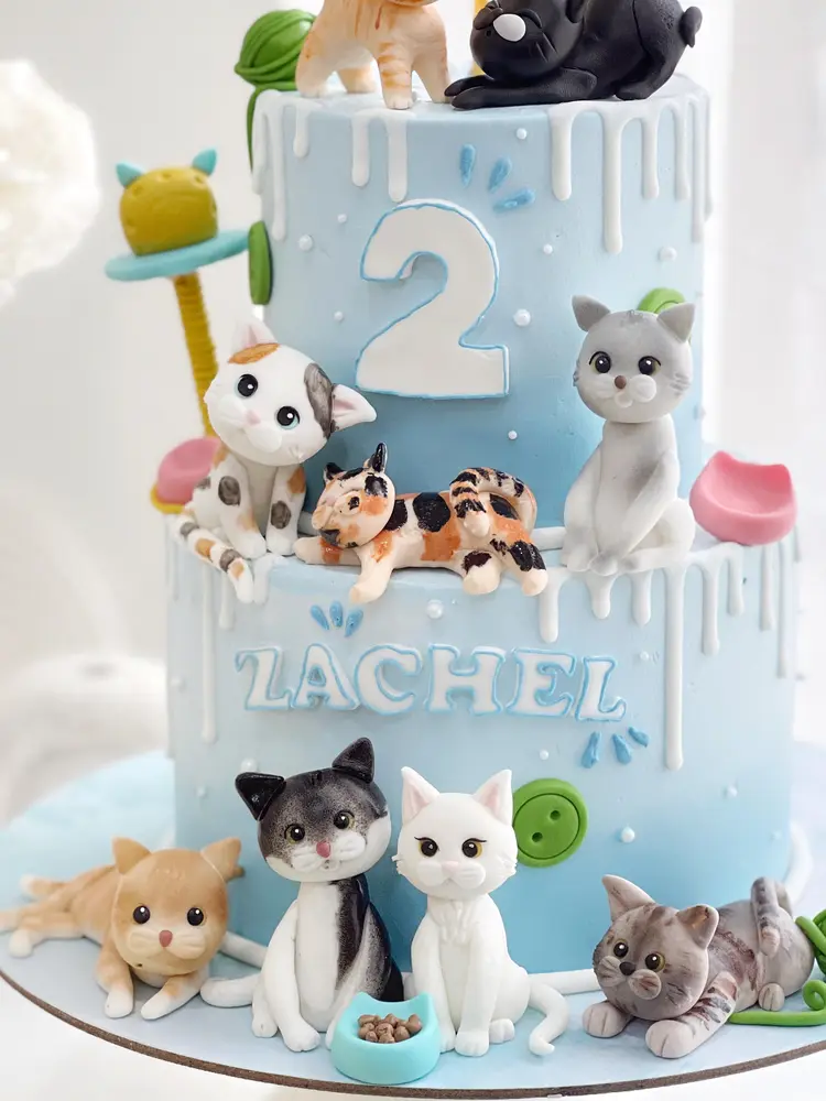 Cake dua tingkat biru muda dengan figur kucing fondant dan angka 2