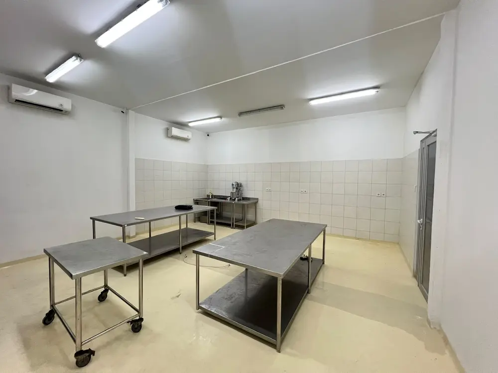 Air-conditioned work room with stainless steel tables and a mixer at the Wanderbakes central kitchen